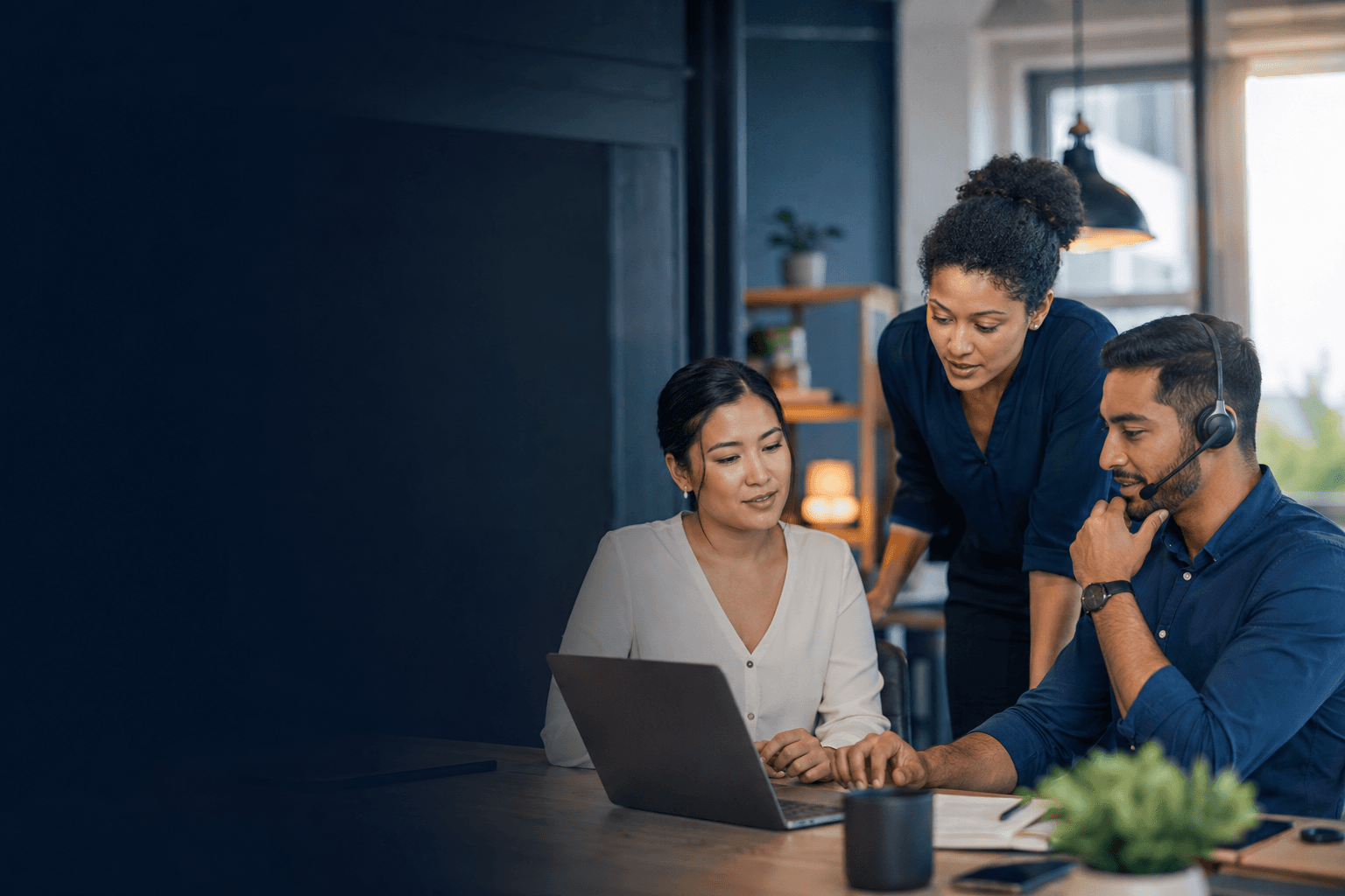 A professional support team collaborating at a laptop and by phone